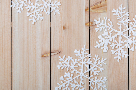 White artificial snowflakes on a light wooden table. Christmas decoration background and copy space for text. Happy Merry Christmas and New year. Closeup.の写真素材