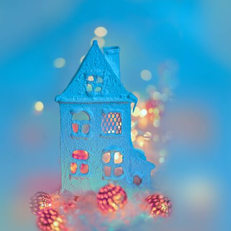 Greeting card Happy New Year and Merry Christmas. Beautiful background of winter decoration for the holiday. House is covered with snow, a garland of metallic luminous balls. Toned image. Copy space.の写真素材