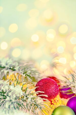 Christmas and New Year Holiday greeting card. Beautiful red balls, pine branches and a garland in the snow. Shallow depth of field. Toned image. Copy space. Blurred bokeh yellow background.の写真素材