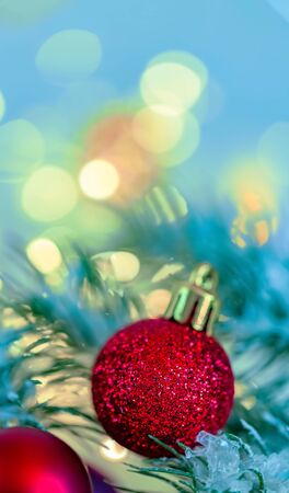 Christmas and New Year Holiday greeting card. Beautiful red balls, pine branches and a garland in the snow. Shallow depth of field. Toned image. Copy space. Blurred bokeh blue background.の写真素材