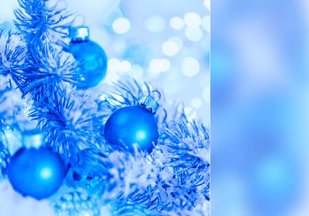 Christmas and New Year Holiday greeting card. Beautiful blue balls, pine branches and a garland in the snow. Blurred bokeh background. Shallow depth of field. Toned image. Copy space. Mockupの写真素材