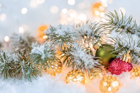 Christmas and New Year Holiday greeting card. Beautiful green and red balls, pine branches and a garland in the snow. Blurred bokeh background. Shallow depth of field. Toned image. Copy space.の写真素材