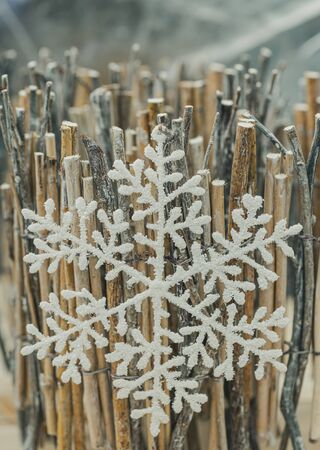 White artificial snowflake on brushwood or fence. Holiday Decoration background and copy space for text. Happy Merry Christmas and New year. Closeup. Shallow depth of field. Toned image.の写真素材