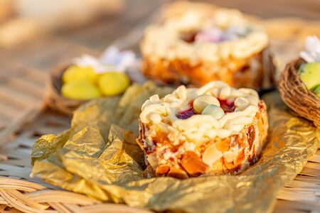 Cake on a wooden table and bronze paper. Easter sponge cake nest. Nuts and oval sweet sweets in the...