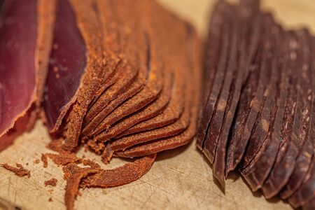 Basturma. Dried meat beef or meat smoked jerky with spices on a wooden cutting board. Armenian food. Beef jerky. Shallow depth of field. Copy space. Closeup. Soft focusの写真素材