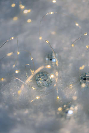 Blurred festive background with  bokeh. Small decorative balls with a mirror and a luminous garland...