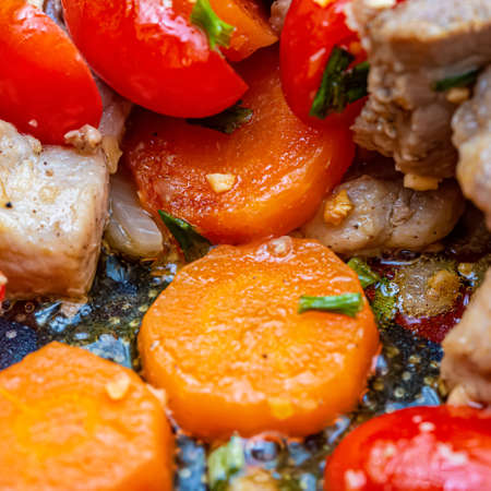 Macro of fried slices of carrots, tomatoes, garlic, green onions and spices with small pieces of meat. Shallow depth of field.の写真素材