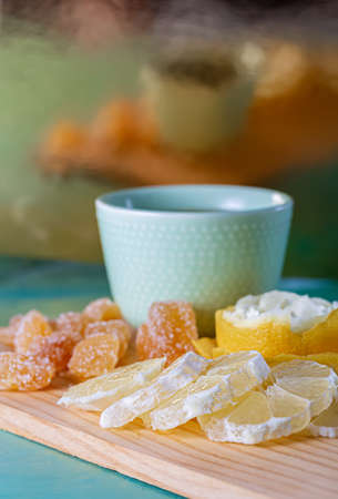 Blue teacup and lemon slices with yellow peel, soft focus of sugar sweet ginger. Blurred vertical background with reflection.の写真素材
