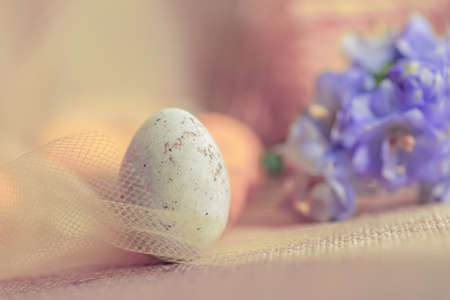Easter sweet white egg in a transparent yellow cloth. Blurred background with purple...