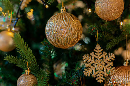Gold festive decorations balls and snowflake on the Christmas tree and beautiful yellow bokeh of...