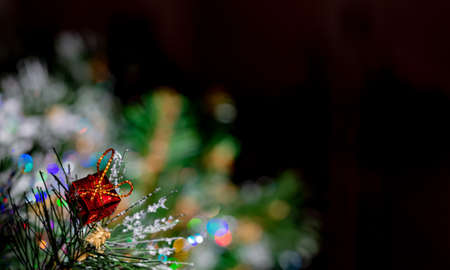 Christmas black blurred background with pine branch and beautiful colored shiny bokeh. Red festive box. Shallow depth of field. Toned image. Copy space.の写真素材