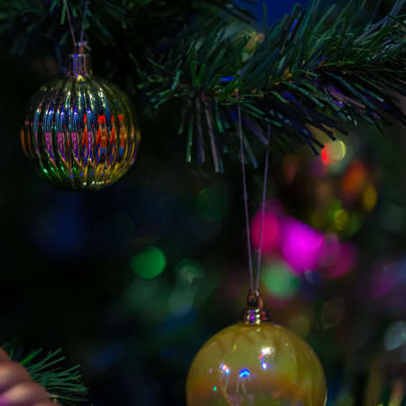 Gold festive decorations balls on the Christmas tree and beautiful colorful bokeh of glowing...