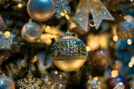 Christmas tree and gold festive glass balls with colored sparkles, beautiful yellow bokeh of glowing...