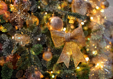 Gold sparkling bow and snowflakes on the Christmas tree. Happy New Year, dark postcard. Shallow depth of field. Toned imageの写真素材