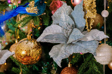 Poinsettia flower with sparkles on a decorated Christmas tree. Yellow bokeh. Soft focus. Shallow depth of field.の写真素材
