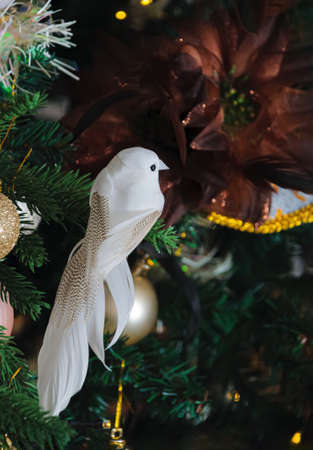 White bird and silk flower on the Christmas tree and a blurred dark background with bokeh. Soft focus.の写真素材