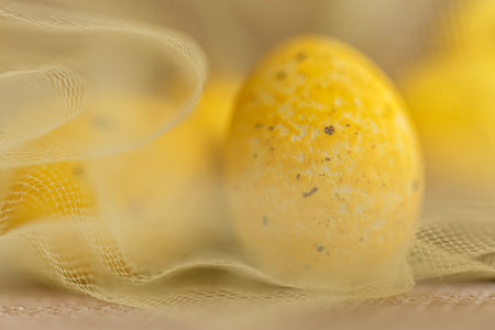 Blurred background of yellow eggs in a transparent cloth on a surface. Greeting cards for Easter. Holiday concept.の写真素材