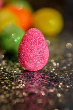 Blurred background with Easter eggs and bokeh on a shiny dark surface. Close-up.The artistic intend and the filters. Film style.の写真素材