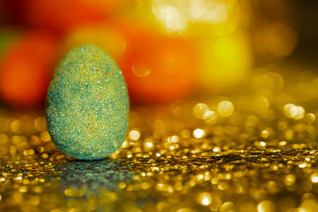 Blurred dark background with Easter eggs and bokeh on a shiny yellow surface.The artistic intend and the filters. Film styleの写真素材