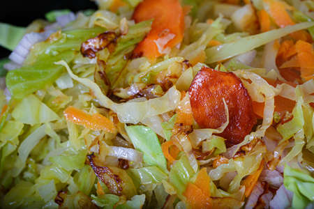 Carrots fried with green cabbage, herbs and onions. Shallow depth of field. Vegetarian food.の写真素材