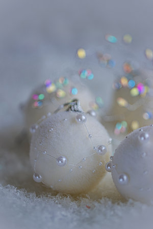 Christmas white balls with pearls on white snow. Blurred background with beautiful bokeh. Shallow depth of field.の写真素材