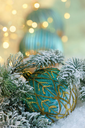 Christmas green balls with golden sparkles on white snow and pine branches. Beautiful blurred background and yellow bokeh.の写真素材
