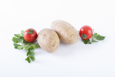 Potatoes and tomatoes on a white background. Potatoes on a white background. Red tomatoes with potatoes.の写真素材