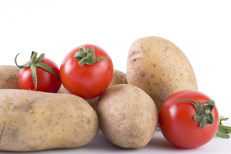 Potatoes and tomatoes on a white background. Potatoes on a white background. Red tomatoes with potatoesの写真素材