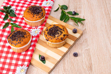 Chocolate muffin and nut muffin, homemade bakery on dark background. Muffin with blueberries on a wooden table. Fresh berries and sweet pastries on the board.の写真素材