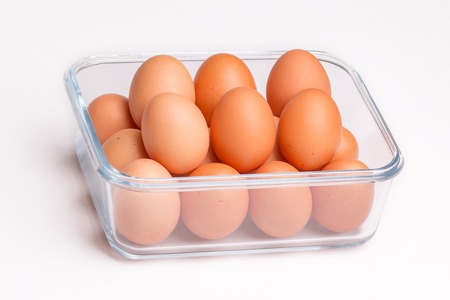 brown eggs in transparent bowl isolated on white