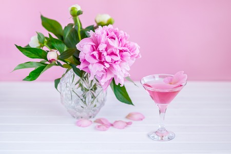 Pink peony next to glass of pink wine.の写真素材