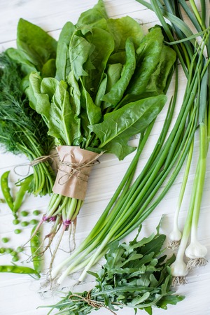 Composition on a white background of green organic vegetarian products: green leafy vegetables, beans, zucchini, garlic, onions, cucumbers, peppers, spinach. view from above. Green foodの写真素材