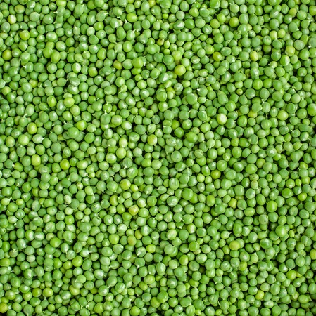 Fresh green peas in a bowl on a white table
