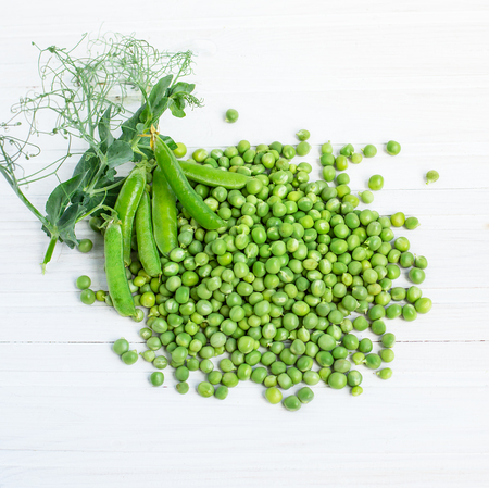 Fresh green peas in a bowl on a white tableの写真素材