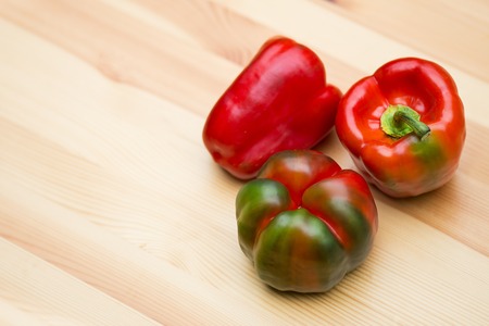 Red bell peppers on wooden table top angle