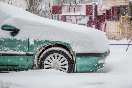 Vehicles covered with snow in a winter blizzard in the parking lot. Snow-covered roads and streets of the city.の写真素材