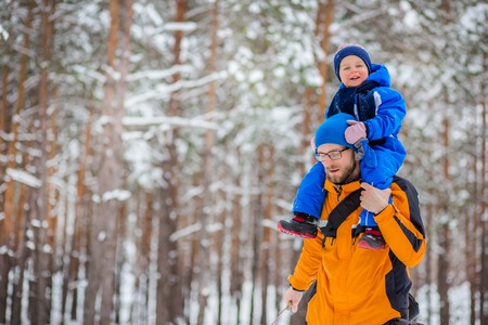 Father walks with his young children in the woods in winter. Winter activities in the snow, sleds and snowballsの写真素材