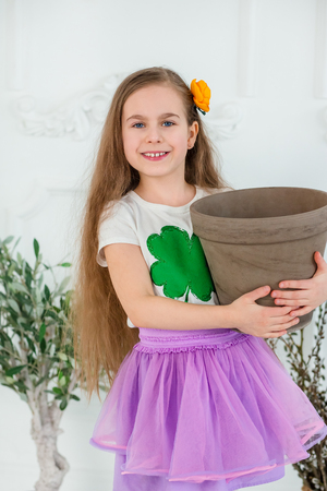 Little cheerful girl with a pot of gold for St. Patrick's day, a wonderful festive infusion.の写真素材