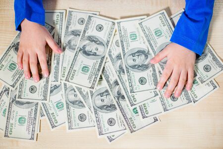 Top view, close-up of hands counting money. Happy child with money dollar, little businessman. Pile...