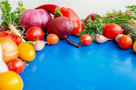 Composition with raw vegetables, tomatoes, peppers, carrots, eggplant, onions on a blue background. Frame of vegetables, copy space for texts.の写真素材