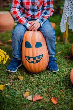 Merry painted pumpkin in the hands of a child. Halloween celebration.の写真素材