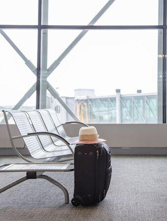 Suitcase in an airport waiting area, concept of lost luggage, one black suitcase in an airport...