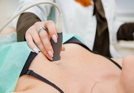 Female doctor working with an ultrasound scanner examining a heart area. Clinical diagnosis of the causes of heart disease.の写真素材