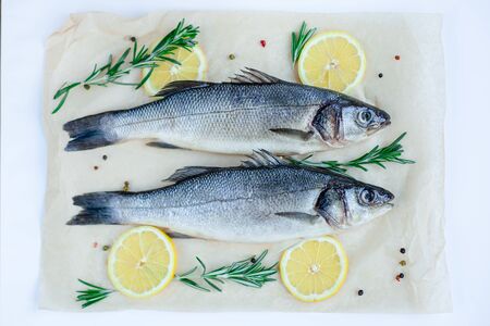 Raw sea bass with spices and herbs on a white slate table. Fresh sea bass. Top view with copy space.の写真素材