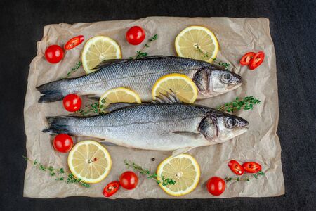Raw fish sea bass with spices and herbs on black slate table. Fresh sea bass. Top view with copy space.の写真素材