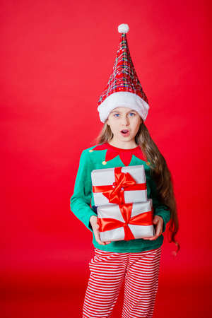 Merry Christmas, happy attractive girl with gifts in a costume of Santa Claus helper elf on a bright...