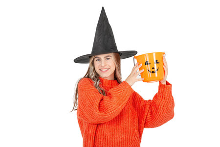 Halloween celebration concept. Portrait of smiling girl in black hat, with pumpkin jack for sweet...