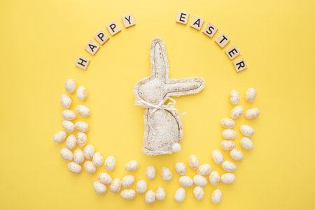 Handmade Easter decor, stylish Easter eggs, textile rabbit on yellow background. Easter wreath shapeの写真素材