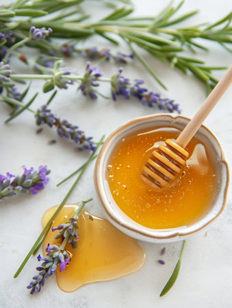 Honey in a ceramic bowl with a honey dipper and lavender flowers on a white surface. Aesthetic food photography and herbal conceptの素材