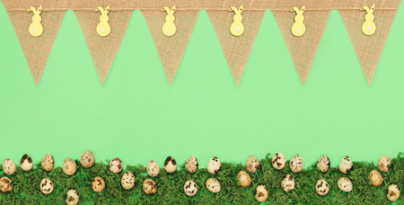 Green background with a burlap banner with Easter bunny cutouts and a row of speckled eggs